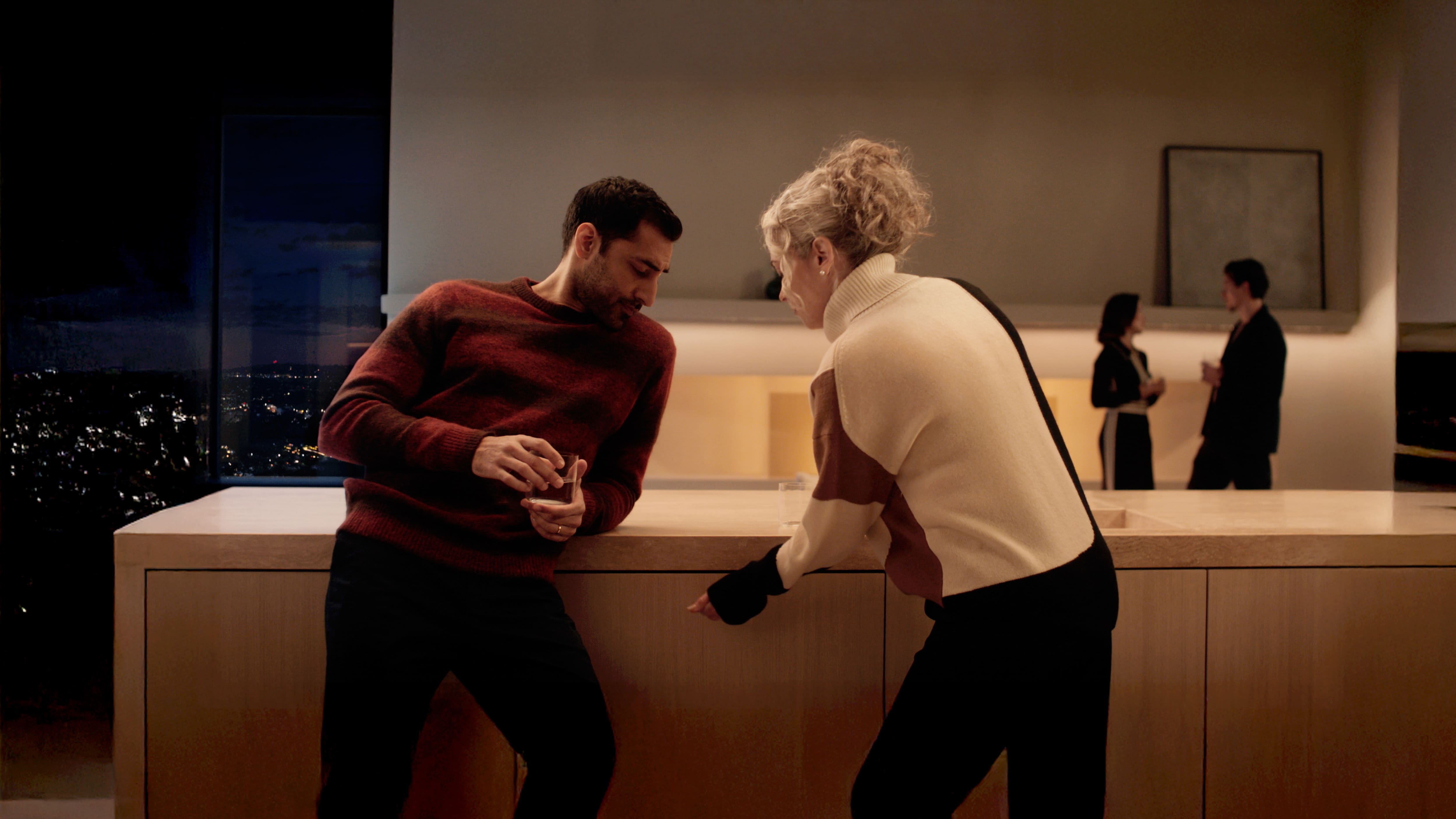 A lady, next to a man in a kitchen setting, knock on the dishwasher to open its door.
