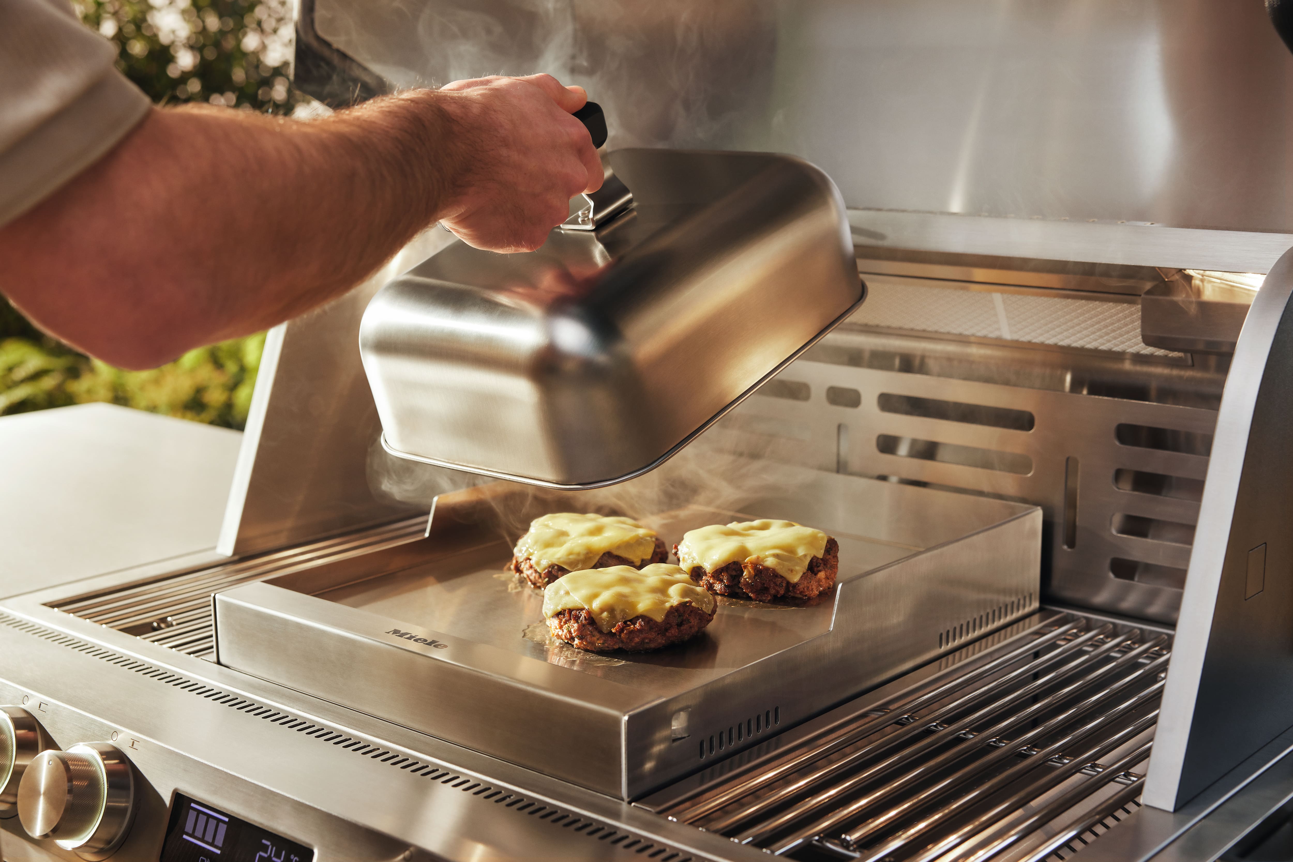 jemand grillt Burger in einer Miele Außenküche jemand grillt Burger in einer Miele Außenküche
