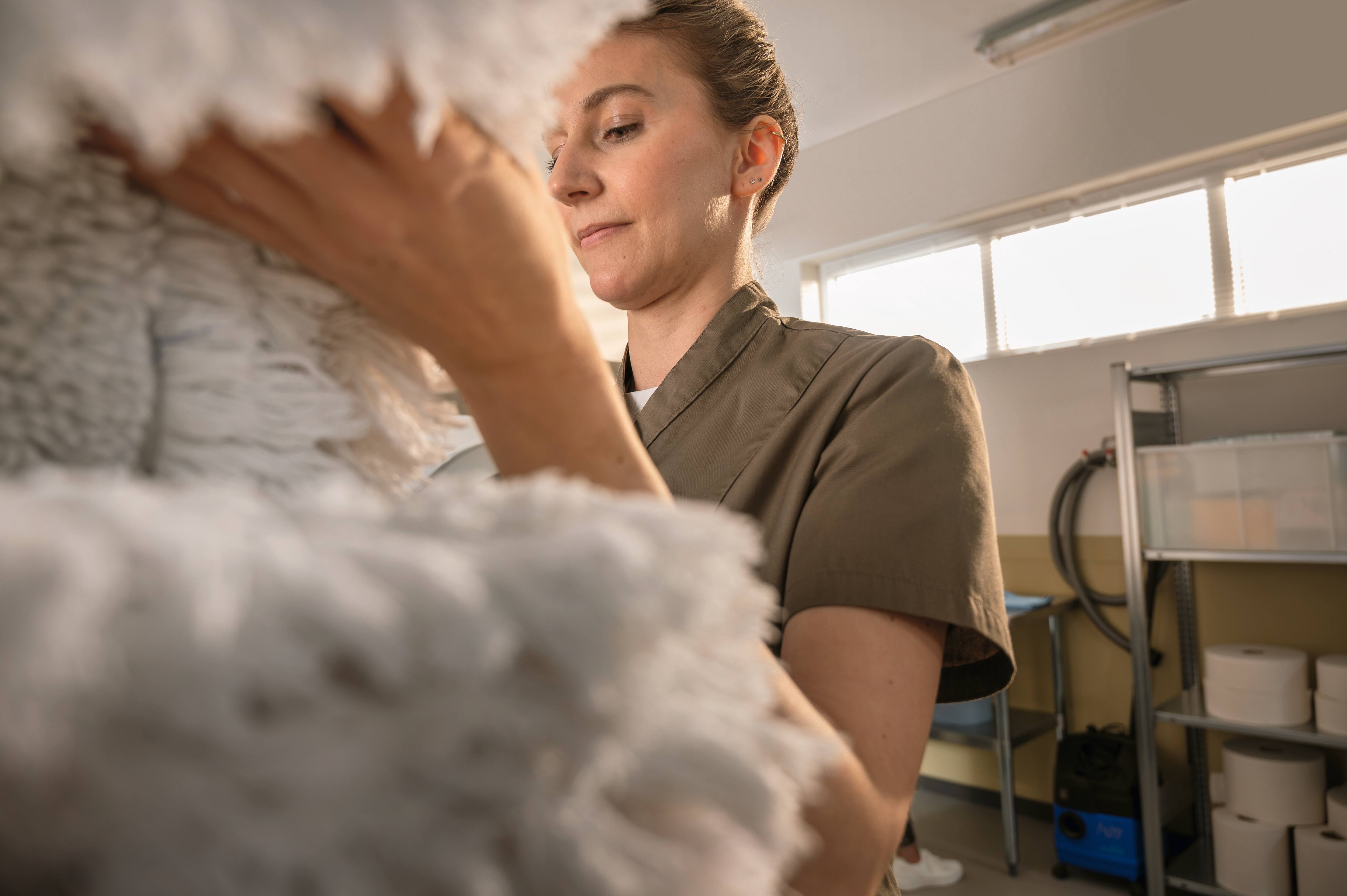 Person hält frisch gewaschene Mop-Textilien in einer professionellen Wäschereiumgebung. 