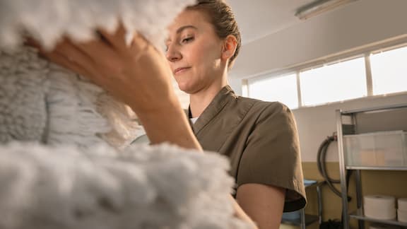 A person handling freshly washed mop heads in a professional laundry setting.