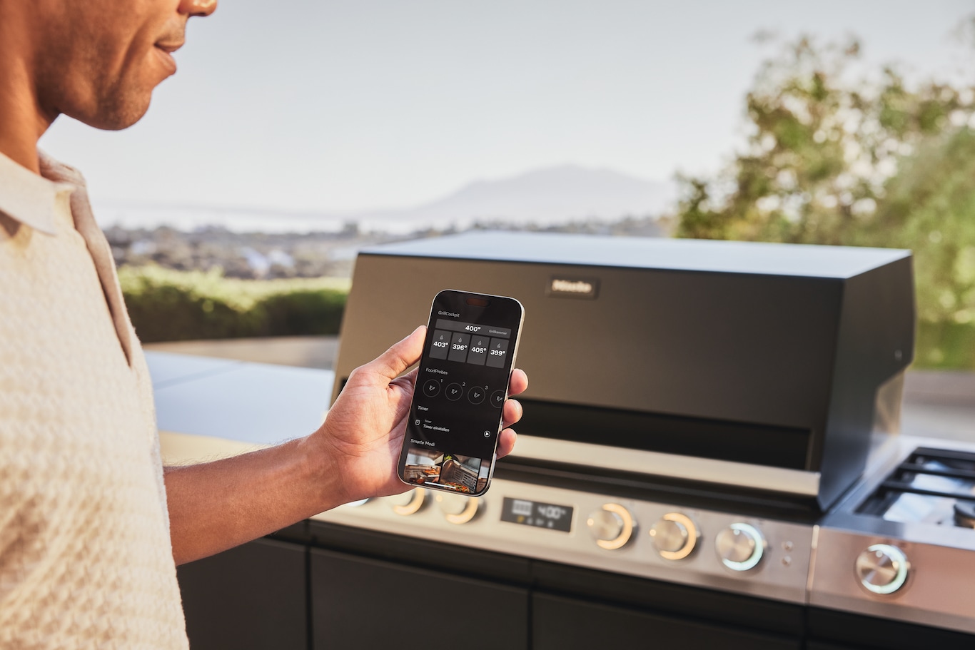 Человек управляет грилем Miele через приложение на смартфоне