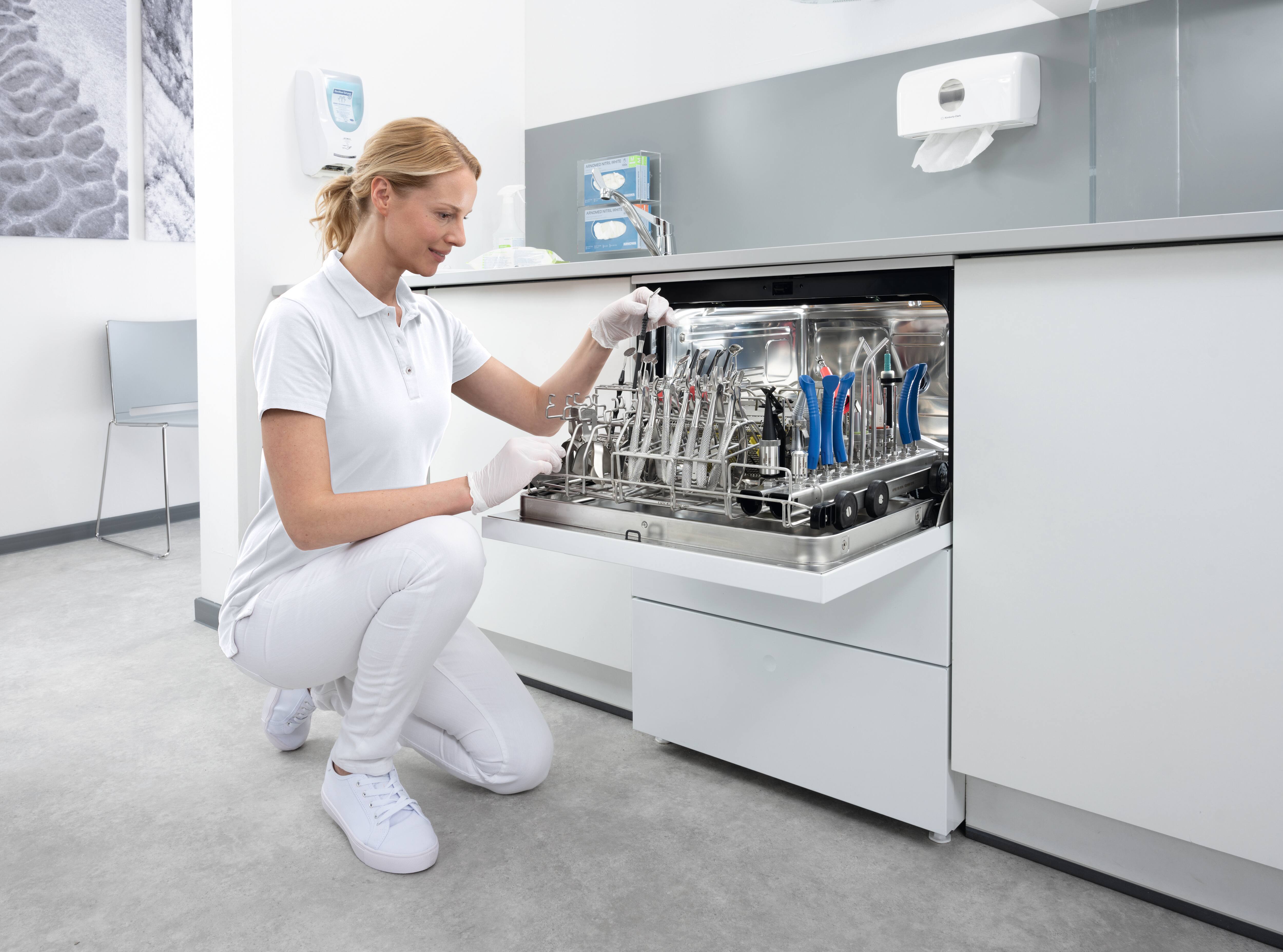 Een tandartsassistente kijkt in de CompactLine thermodesinfector gevuld met  tandheelkundige instrumenten