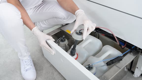 Een hand opent de deur van een CompactLine thermodesinfector