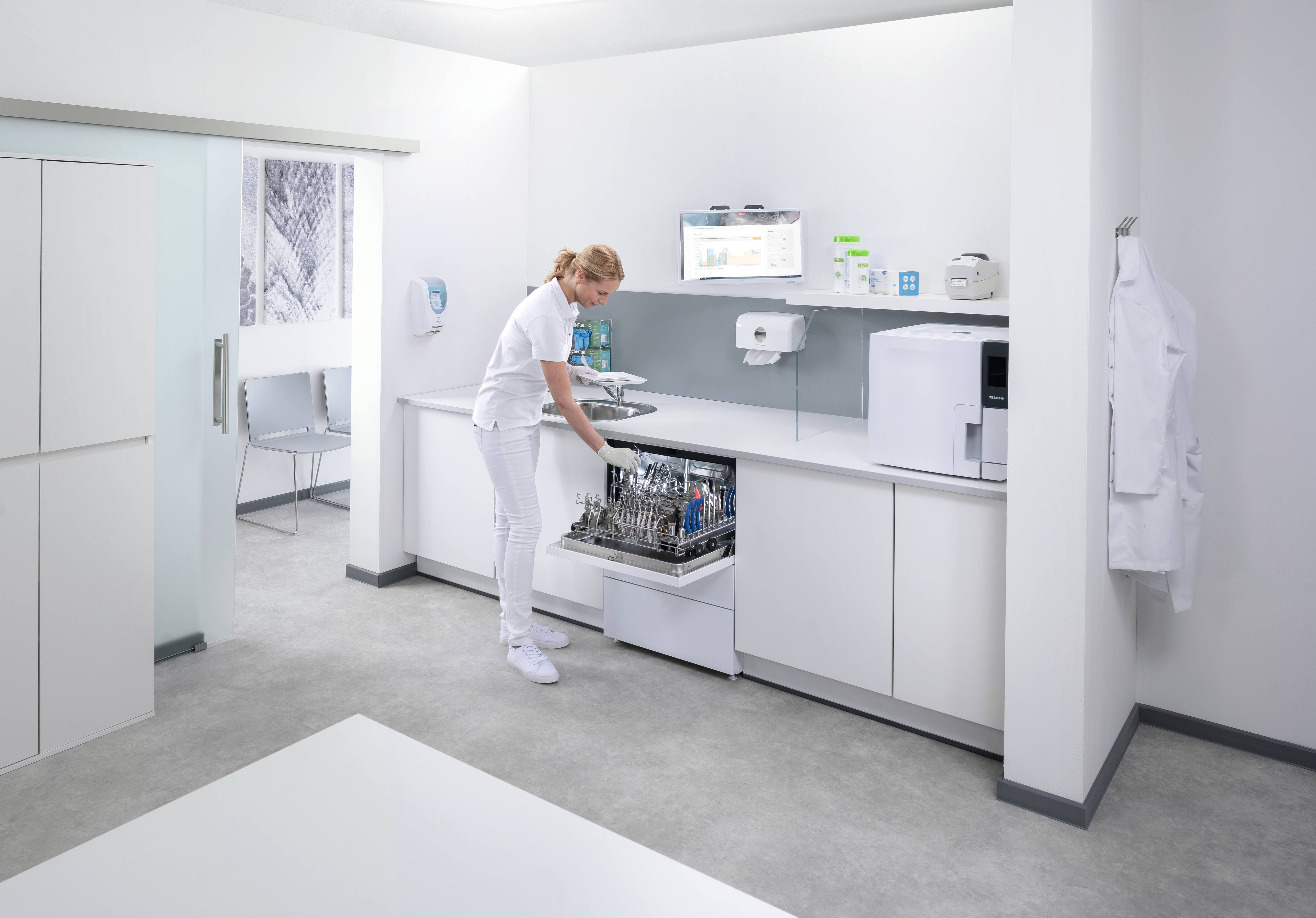 Een tandartsassistent maakt een CompactLine thermodesinfector in de behandelkamer leeg