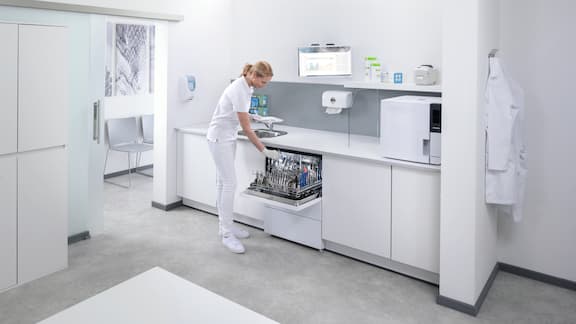 Een tandartsassistent maakt een CompactLine thermodesinfector in de behandelkamer leeg