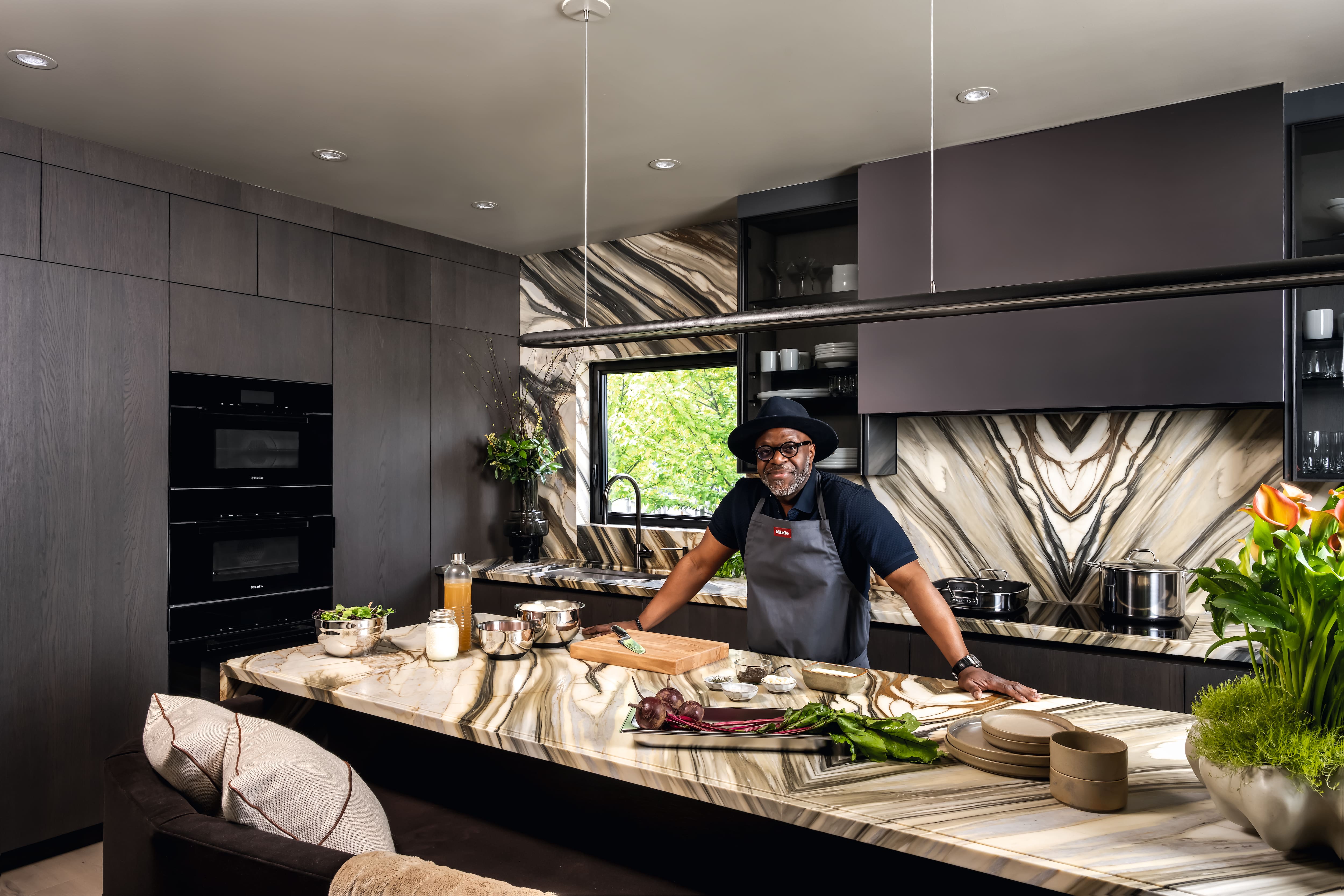A person stands at a marble kitchen island preparing ingredients.