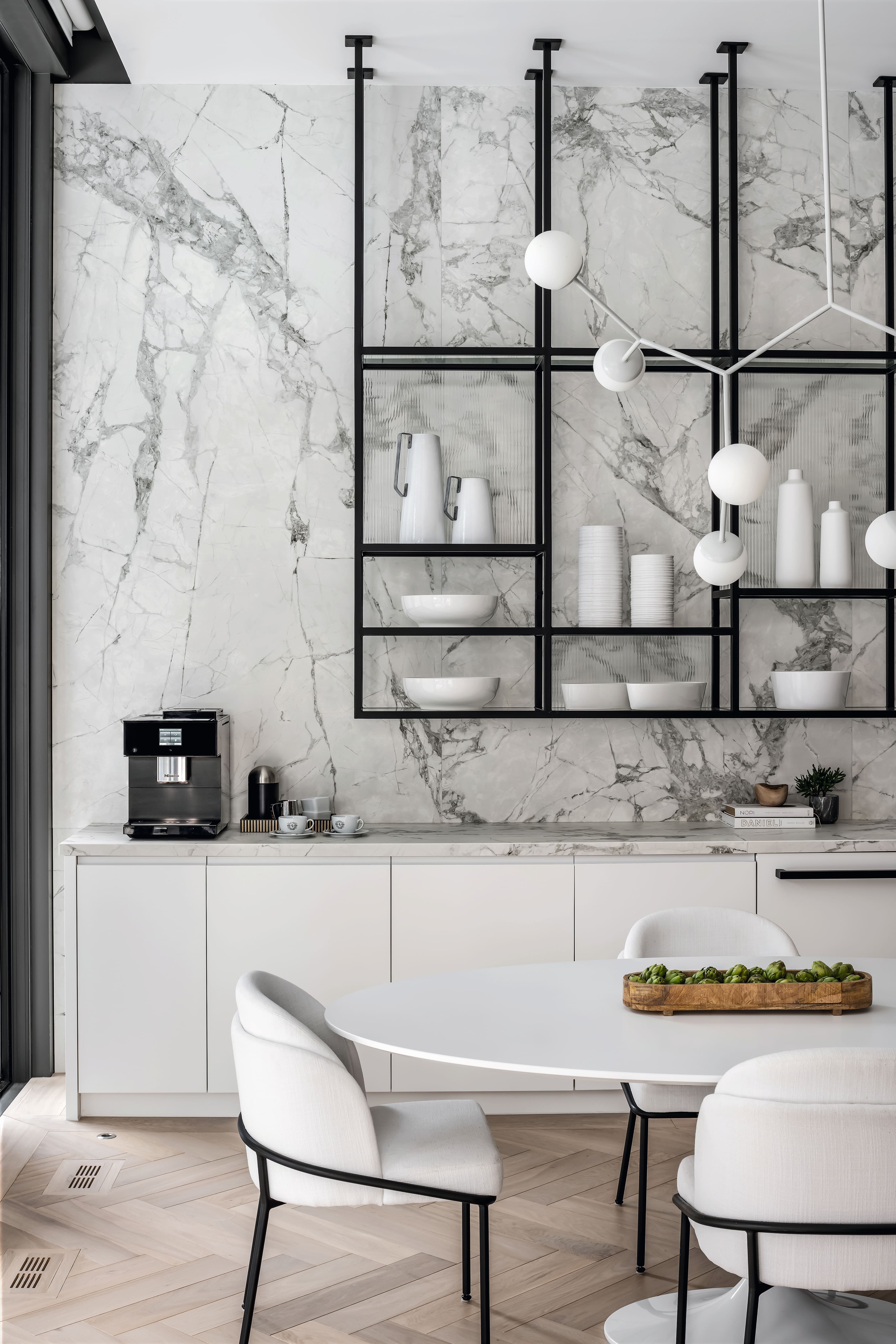 Modern dining area with a marble wall and a coffee machine on a white counter.