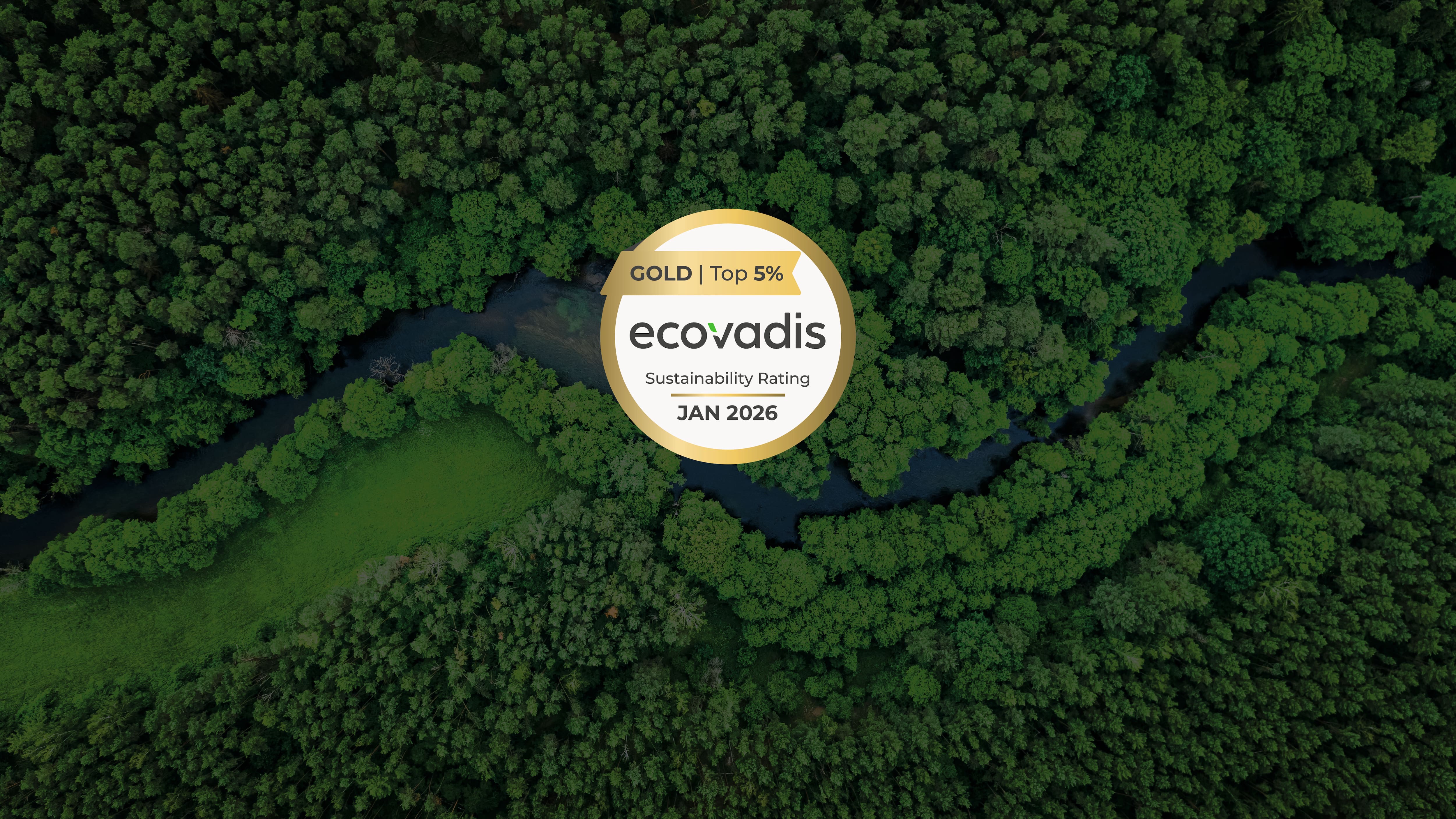 Ilmakuva vehreästä metsästä, jossa mutkitteleva joki ja keskellä oleva merkki, jossa lukee “GOLD | Top 5%, EcoVadis, Sustainability Rating, JAN 2026”