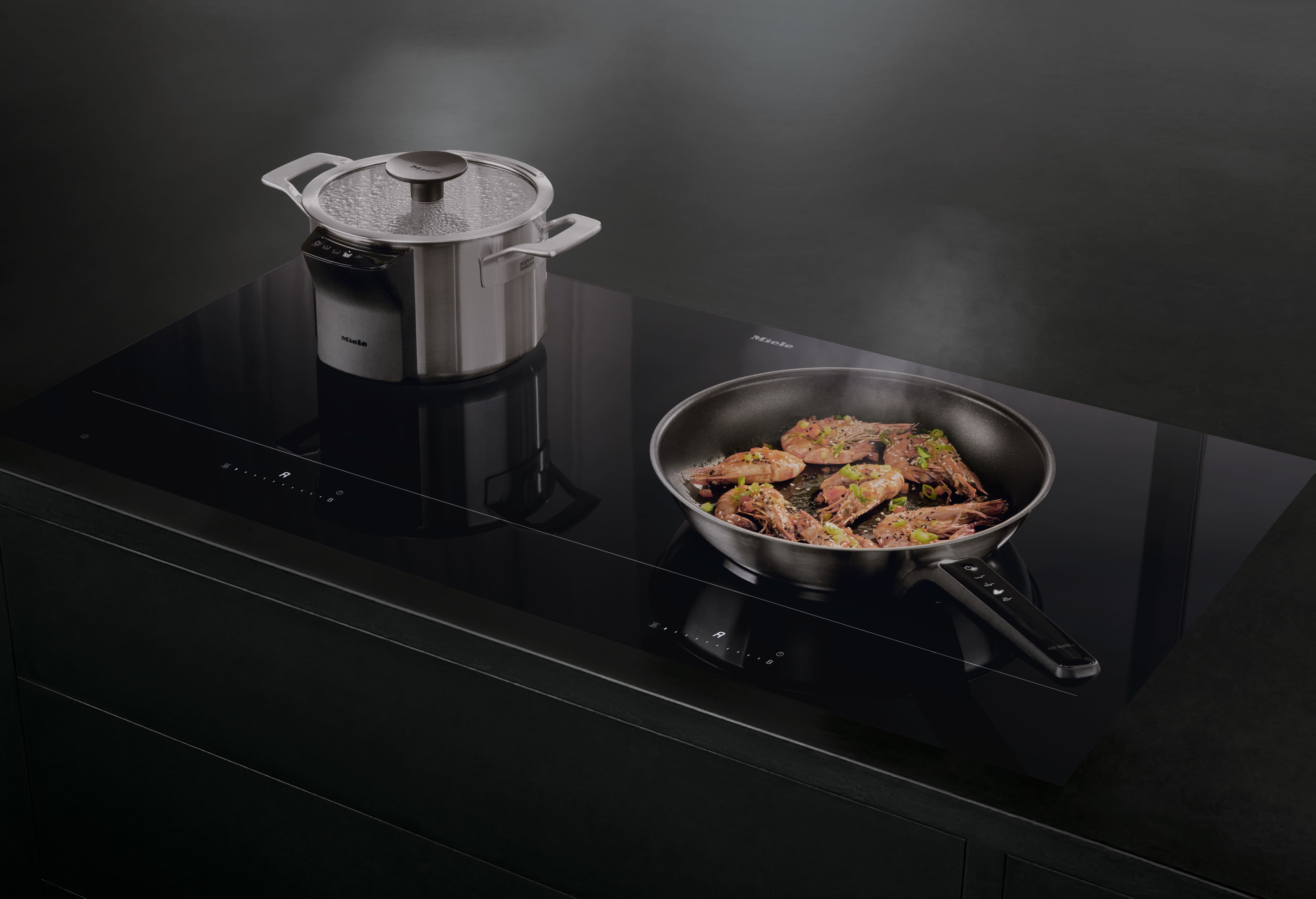 Une poêle et une casserole posées sur une plaque de cuisson Miele