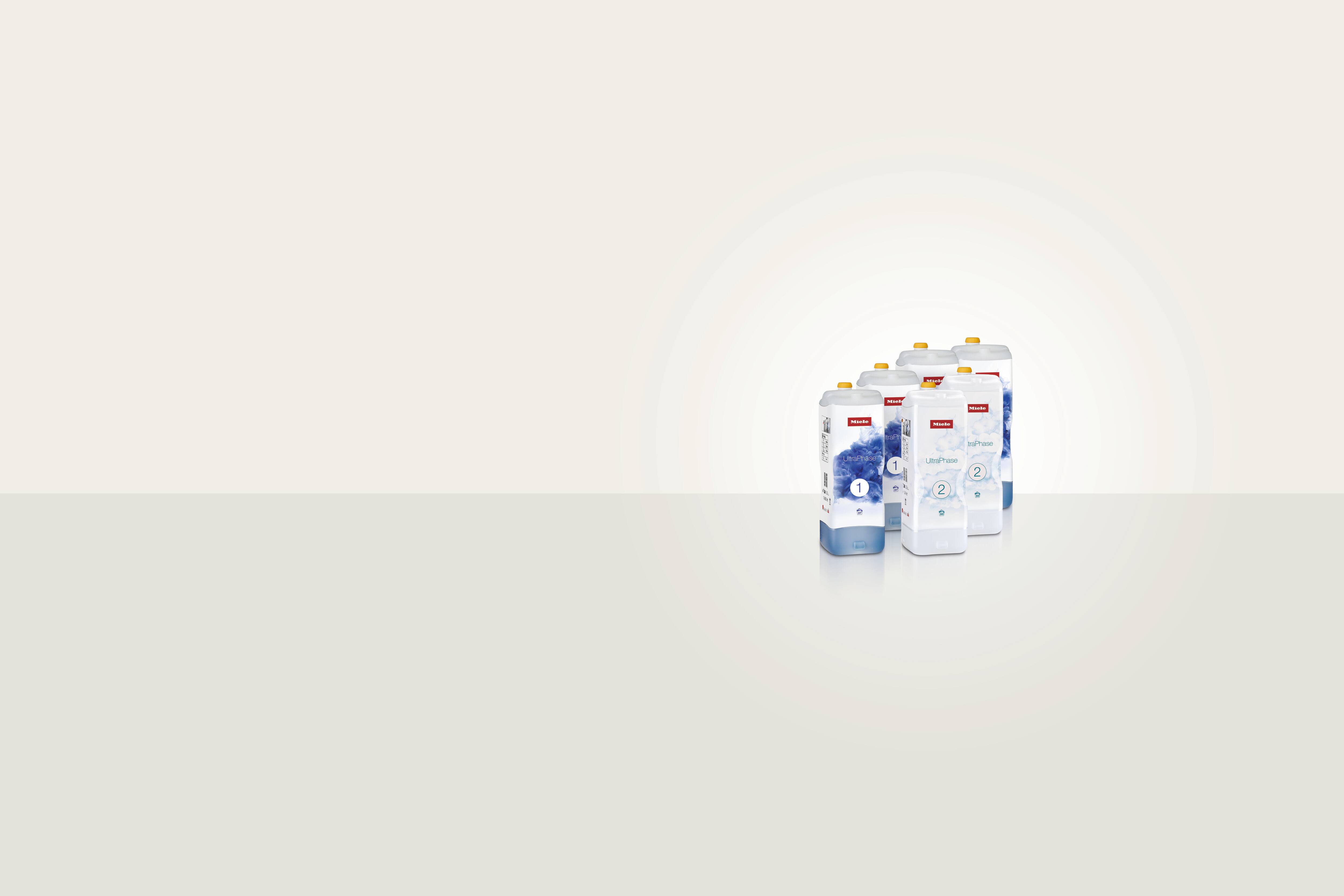 Vier Kartuschen mit UltraPhase 1 und zwei Kartuschen von Ultra Phase 2 Waschmitteln stehen nebeneinander in einem virtuellen Raum mit grauem Hintergrund.